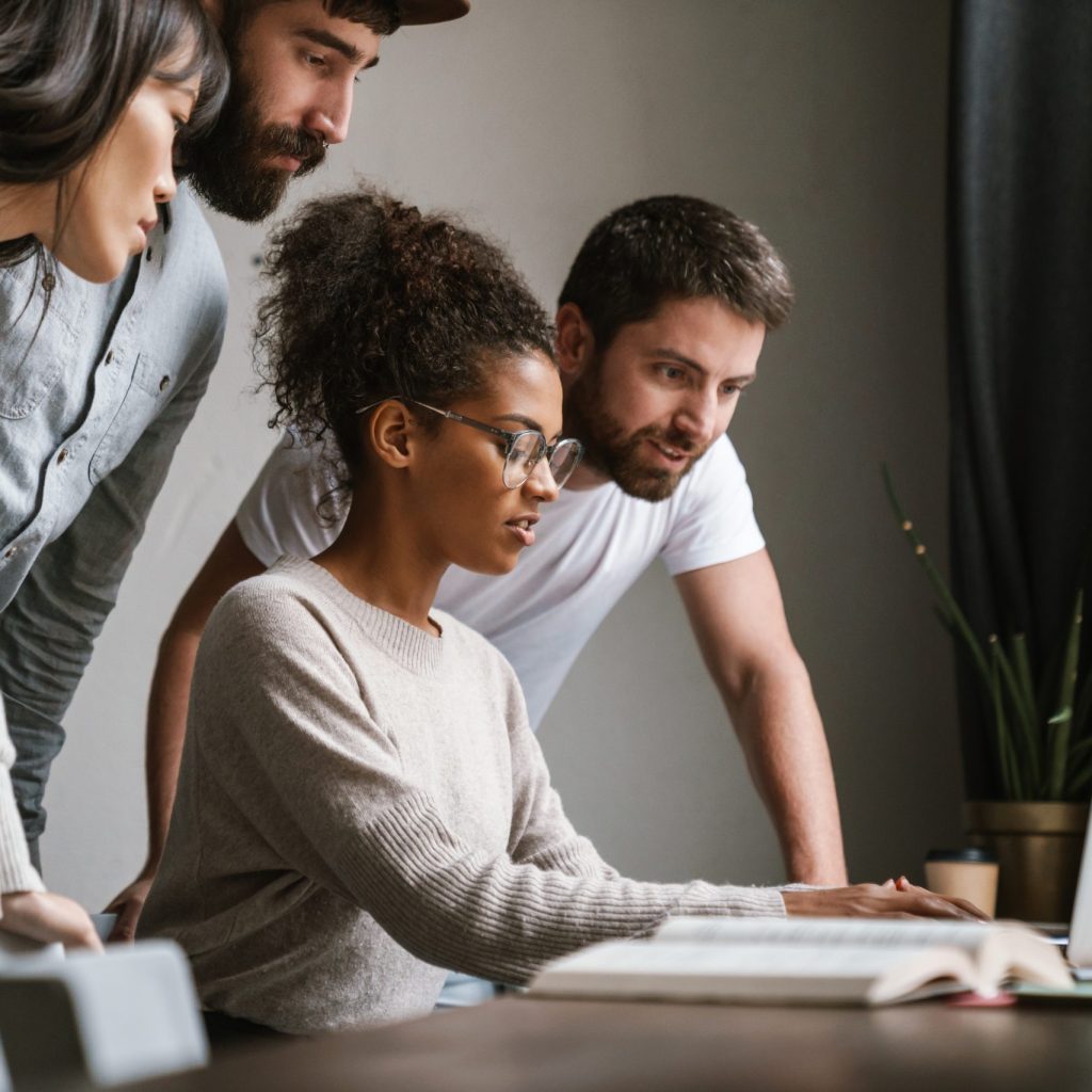 Group of people huddled at a computer.